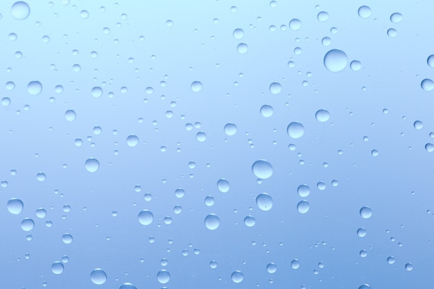 Gotas de agua sobre la superficie de vidrio azul