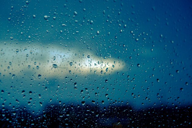 Gotas de agua sobre vidrio contra el azul cielo nublado en la noche