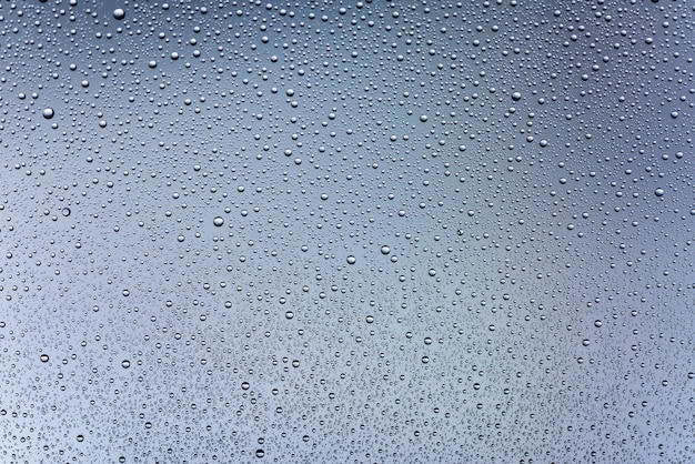 Gotas de agua sobre el vidrio sobre un fondo gris