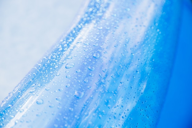 gotas de agua - en la superficie azul de una rueda de juguete inflable. Colchón de playa inflable con gotas de agua en un día soleado. Superficie de la piscina infantil azul brillante con gotas de agua. Piscina de verano