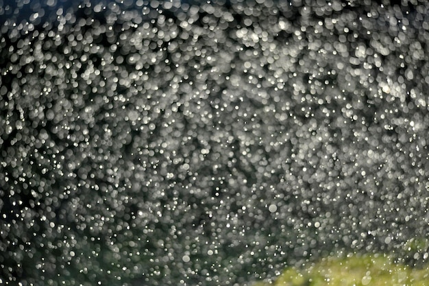 Gotas de agua voladoras contra los rayos del sol sobre un fondo oscuro