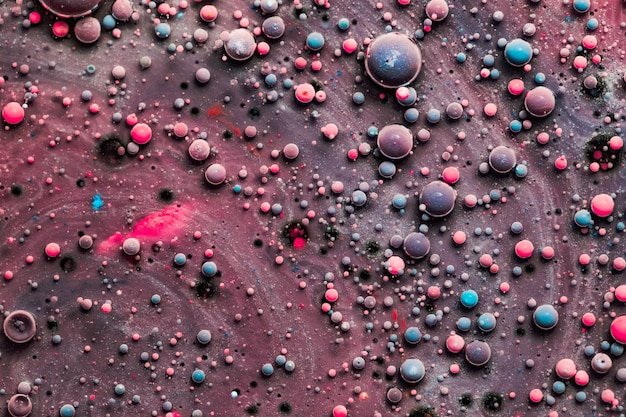 Gotas de color flotando en aceite y agua sobre un colorido subterráneo con efecto de pintura al óleo. Macro