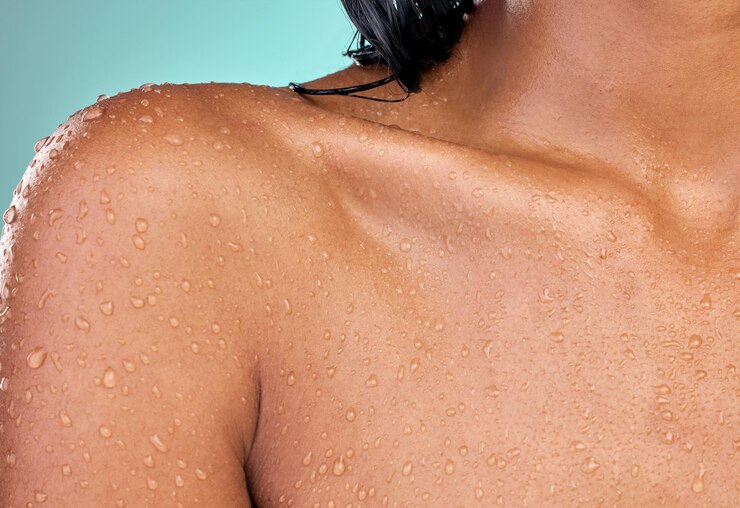 Foto gotas de água chuveiro e clavícula de mulher para cuidados com a pele com segurança de bem-estar de bactérias e higiene em estúdio líquido de dermatologia e corpo modelo com limpeza da pele para a saúde por fundo azul