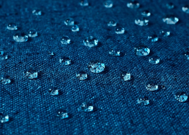 Gotas de água da chuva em tecido impermeável azul.