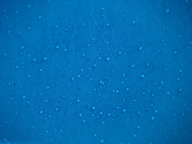 Gotas de água no tecido da membrana impermeável. visualização de detalhes da textura de tecido impermeável sintético azul. orvalho da manhã na barraca.