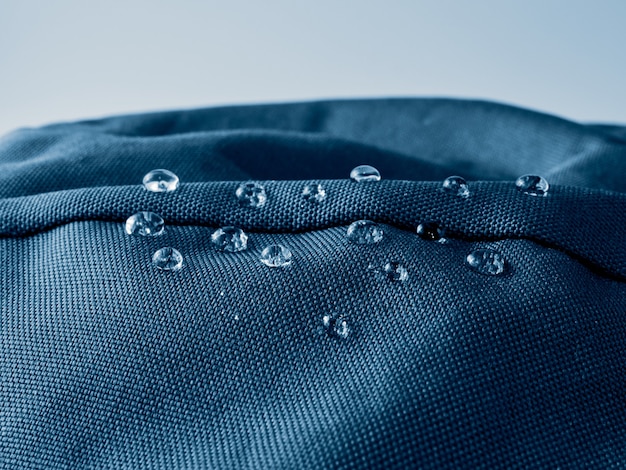 Gotas de água no tecido da membrana impermeável. visualização de detalhes da textura de um pano impermeável azul.