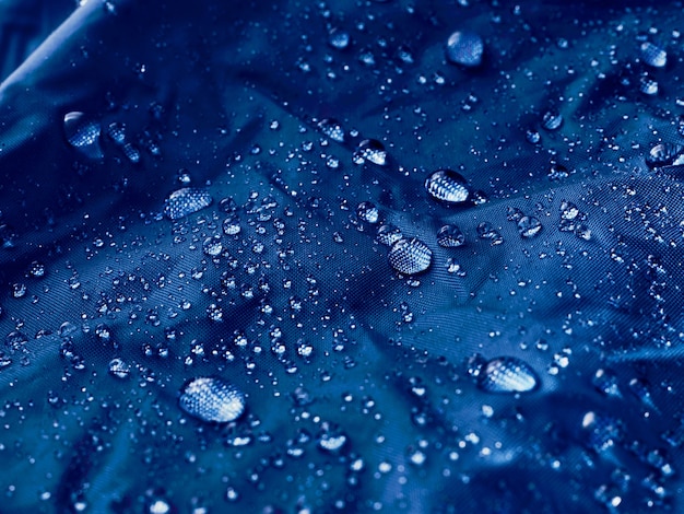 Gotas de água no tecido da membrana impermeável. Visualização de detalhes da textura de um pano impermeável azul.