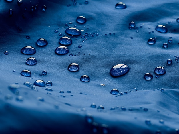 Gotas de água no tecido da membrana impermeável. Visualização de detalhes da textura de um pano impermeável azul.