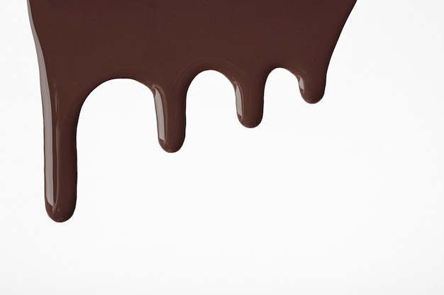 Foto gotas de chocolate escuro líquido de tinta fluem sobre fundo branco isolado