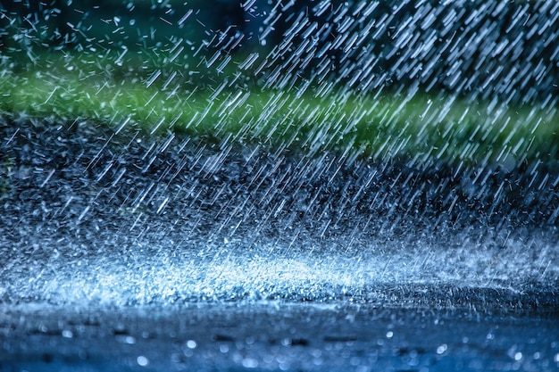 Gotas de chuva caem no asfalto de perto Deterioração das condições climáticas Resfriamento por precipitação
