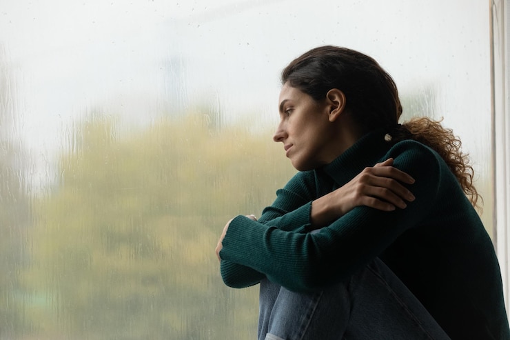 Foto gotas de chuva como lágrimas triste solitária latina mulher sentar-se na janela em humor melancólico olhar para a chuva lá fora sentindo seu coração quebrado jovem mulher pensativa abraçar-se sofrer de amor não respondido espaço de cópia