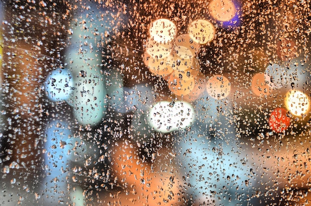 Gotas de chuva contra o vidro azul Rua turva da cidade noturna Fundo abstrato outonal