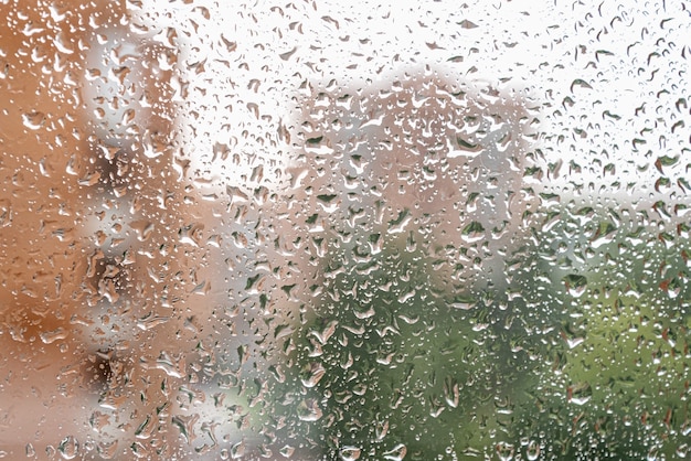 Gotas de chuva escorrem no vidro da janela em dia chuvoso