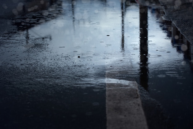 Gotas de chuva espirrando durante a queda de chuva forte à noite, foco seletivo. Fundo de temporada chuvosa.