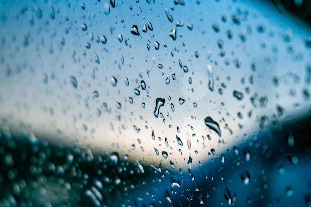 Gotas de chuva na superfície dos vidros da janela com gotas do pôr do sol em spray de vidro no fundo da janela para foco seletivo de exibição de texto escuro