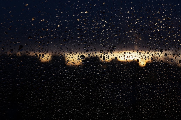 Gotas de chuva no painel da janela. O plano de fundo de uma janela molhada ao pôr do sol. Pôr do sol depois da chuva