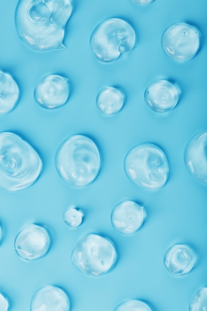 Foto gotas de gel com ácido hialurônico na forma de uma mancha de textura brilhante em uma superfície azul