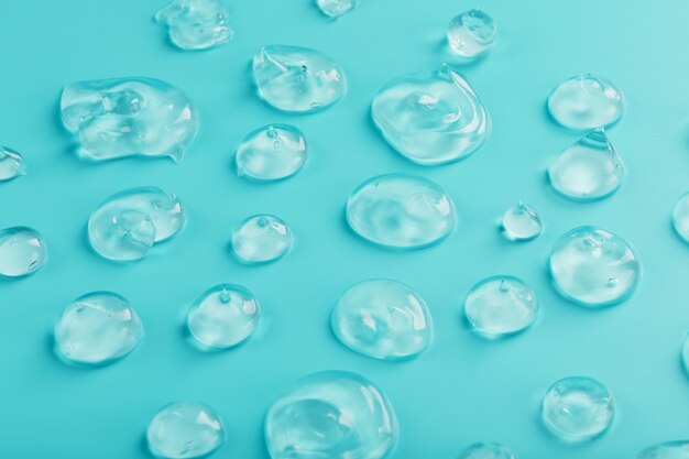 Gotas de gel com ácido hialurônico na forma de uma mancha de textura brilhante em uma superfície ciano