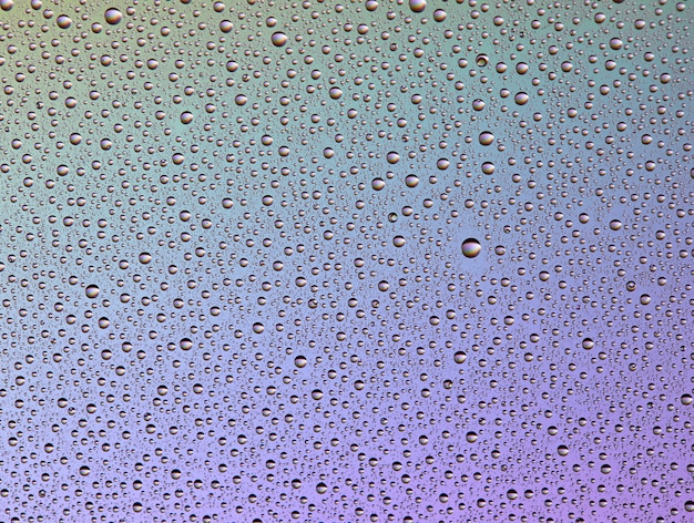 Gotas em vidro de diferentes tamanhos e cores em um fundo colorido, textura