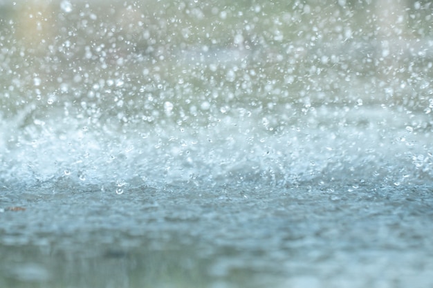 Gotas de lluvia cayendo en un gran charco de asfalto urbano en la ciudad.