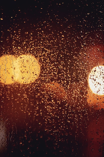 Gotas de lluvia y luces borrosas a través de una ventana.