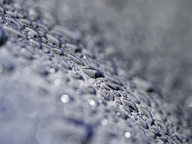 Las gotas de lluvia en el metal azul de cerca macro