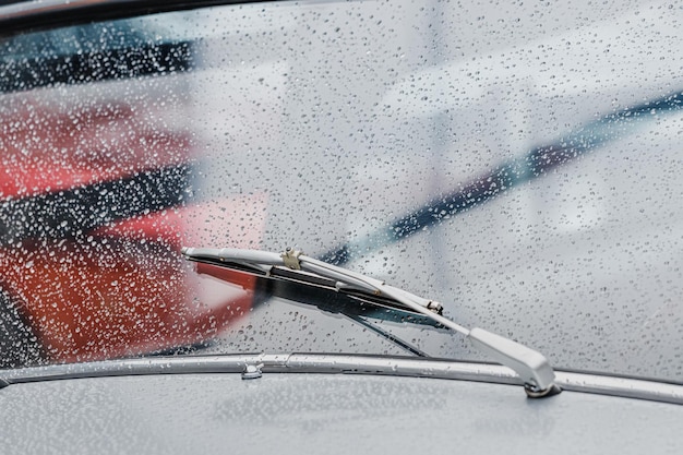 Gotas de lluvia en el parabrisas y limpiaparabrisas en funcionamiento de un automóvil retro Estado de ánimo cinematográfico y atmosférico de la imagen