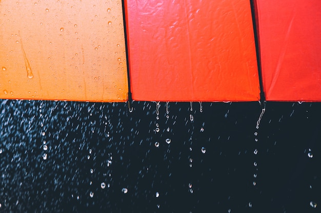 Gotas de lluvia y paraguas sobre fondo negro