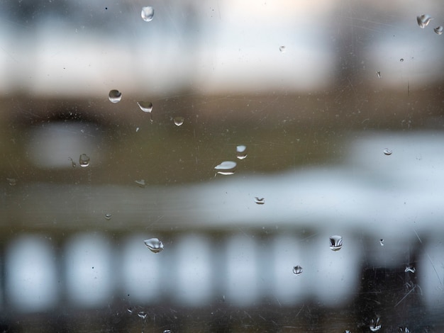 Gotas de lluvia sobre el cristal sucio. Al fondo, un paisaje rural borroso