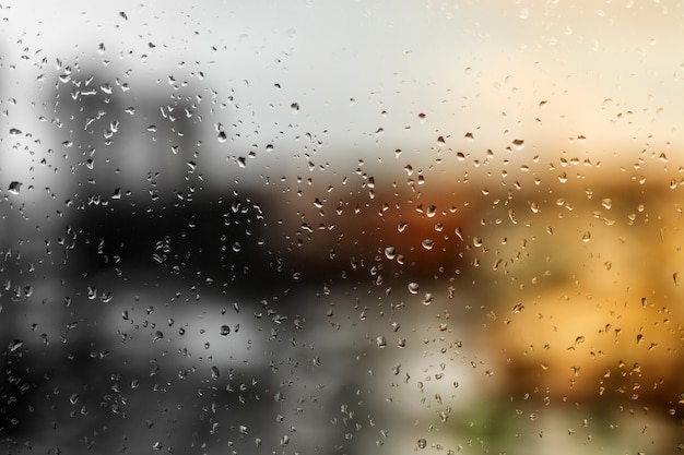 Gotas de lluvia sobre el cristal de una ventana, edificios de la calle en el fondo.