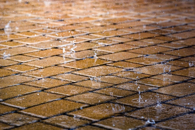 Gotas de lluvia sobre el piso mojado de baldosas de la calle en la ciudad durante la lluvia. Acera de la ciudad en día lluvioso.