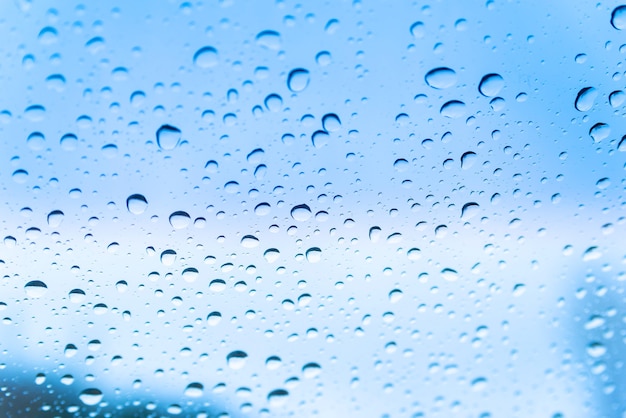 Gotas de lluvia sobre el vidrio contra un nublado cielo azul