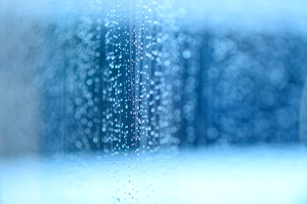 Gotas de lluvia sobre el vidrio / fondo azul.