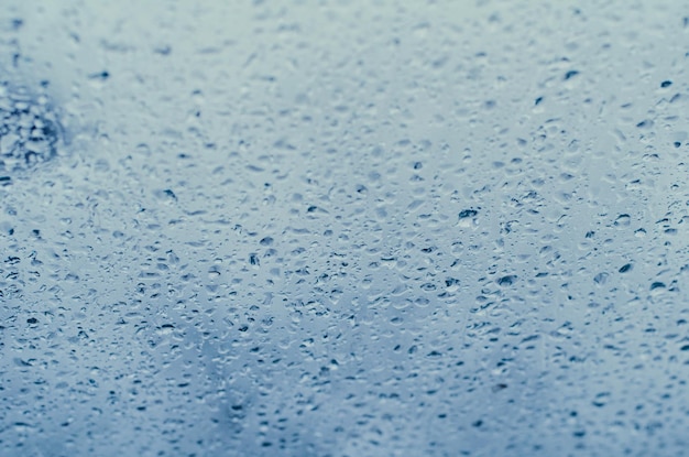 Gotas de lluvia sobre el vidrio de la ventana en tonos azules