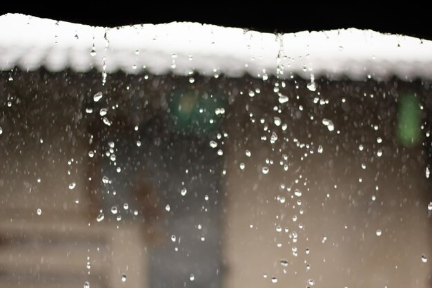 Gotas de lluvia desde el techo continuamente con fondo de naturaleza verde borroso