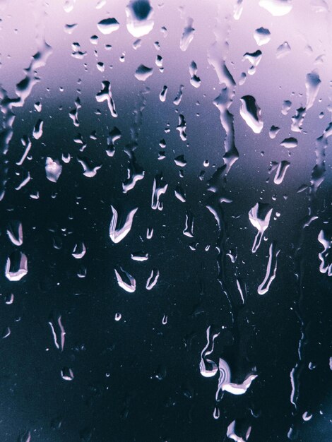 gotas de lluvia en una ventana con un cielo púrpura en el fondo