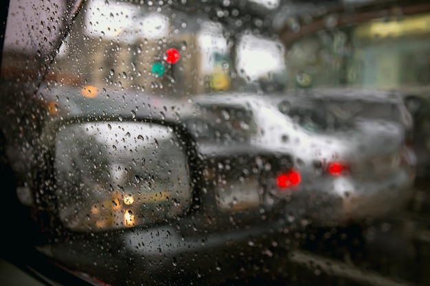 Gotas de lluvia en la ventana del coche en la ciudad de atascos de tráfico