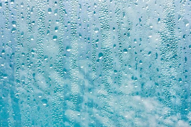 gotas de lluvia en la ventana y fondo de cielo azul