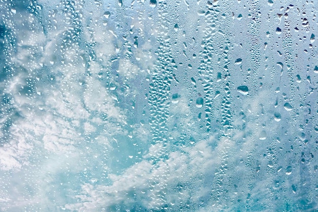 gotas de lluvia en la ventana y fondo de cielo azul