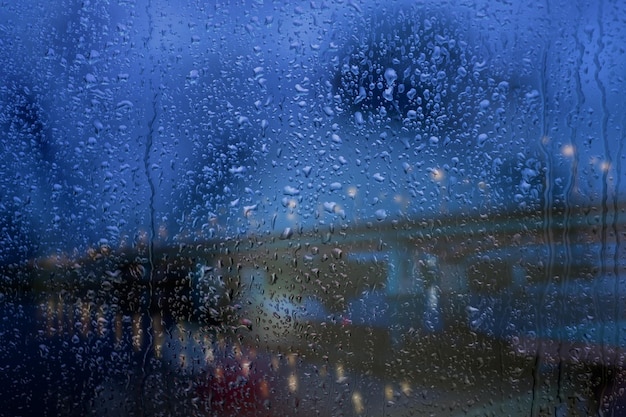 Gotas de lluvia de la ventana lluviosa sobre el vidrio contra el fondo de la carretera y el puente Camino seguro a casa