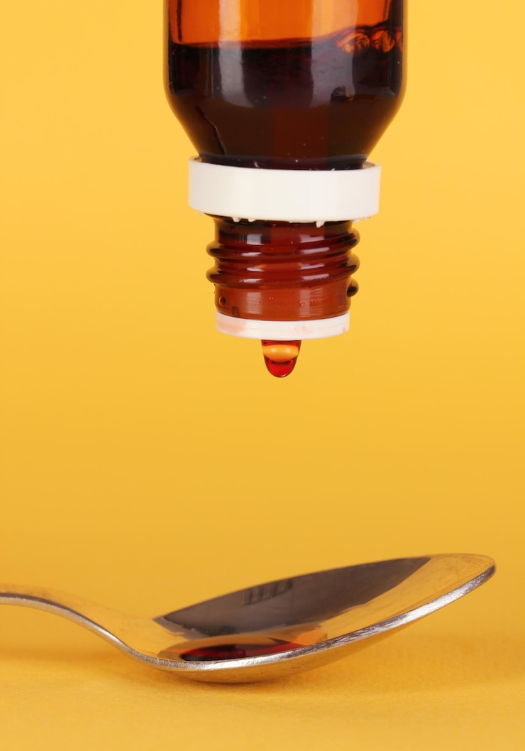 Foto gotas médicas en cuchara sobre fondo amarillo