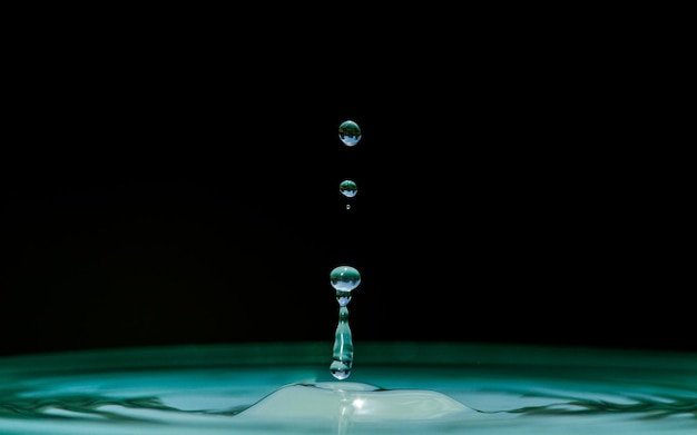 Gotas que caen sobre el agua ondulada contra un fondo negro