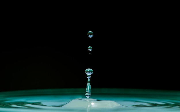 Foto gotas que caen sobre el agua ondulada contra un fondo negro