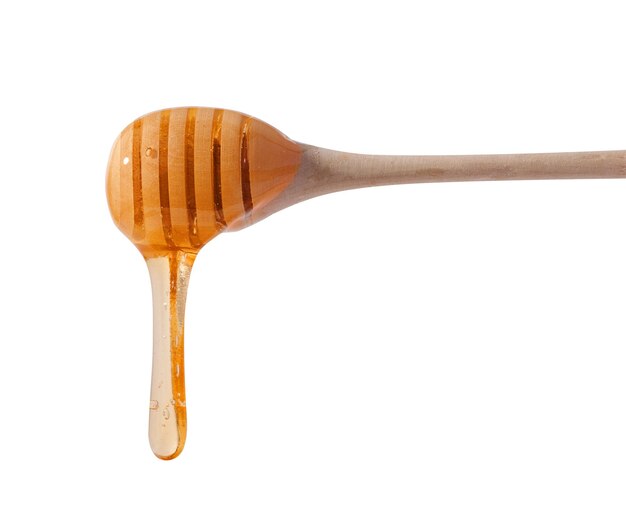 Gotas que fluyen de miel amarilla de un palo de madera sobre un fondo blanco aislado
