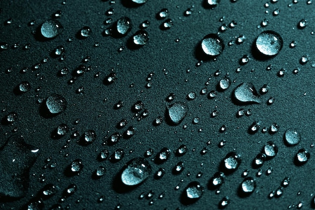 Gotas redondas de agua sobre fondo oscuro A través de gotas transparentes de agua pasan rayos de luz Vista desde arriba Hermosa espalda para protector de pantalla Fondo abstracto