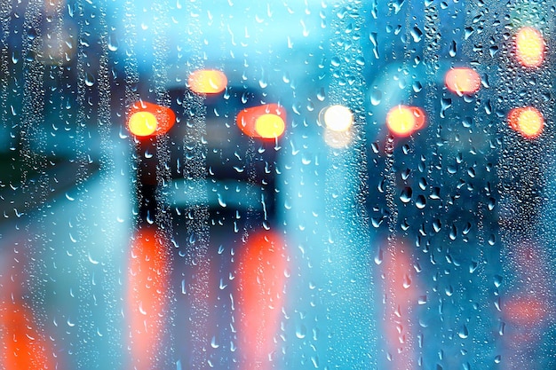 Gotas sobre vidrio auto carretera lluvia noche de otoño / fondo abstracto de otoño en la ciudad, tráfico de automóviles, viaje romántico en coche