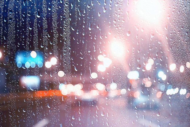 Gotas sobre vidrio auto carretera lluvia noche de otoño / fondo abstracto de otoño en la ciudad, tráfico de automóviles, viaje romántico en coche