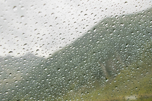 Gotas sobre el vidrio del coche y el fondo del paisaje de montaña