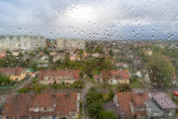 Gotas sobre vidrio en el fondo de la ciudad en tiempo nublado