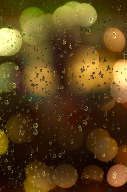 Gotas en la ventana y luces de colores amarillas en la noche.